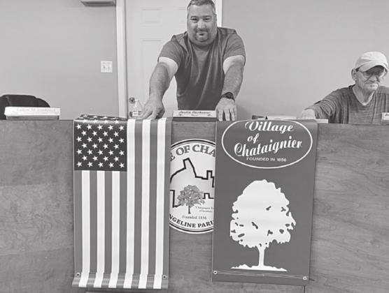 NEW BANNERS ARE UNVEILED - Chataignier Mayor Justin Darbonne (center) unveils new American Flag and Village of Chataignier banners during the council meeting Also pictured on the right is Councilman J.B. Brasseaux. (Gazette photo by Nancy Duplechain)