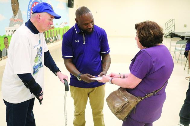 Suzy Fontenot (right) presents new Ville Platte High School head football coach Chris Bland (center) with a copy of Sharpened Iron: The Tee Cotton Bowl Story. Pictured on the left is Tee Cotton Bowl co-founder Tim Fontenot. (Gazette photo by Tony Marks)