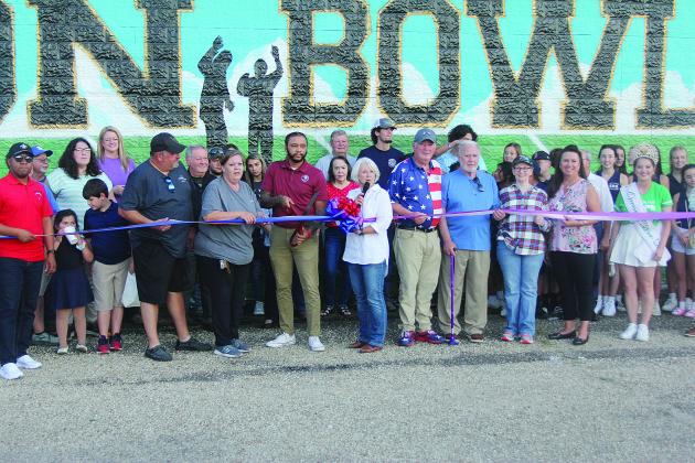 Among those pictured at the Tee Cotton Bowl mural dedication ceremony are (from left) Chris and Connie Lamke, Thaddaeus Arvie, Dr. Gwen Fontenot, Tim Fontenot, Ronnie and Joan Landreneau, Renee Brown, and Queen Cotton Shelbi Rials. (Gazette photo by Tony Marks)