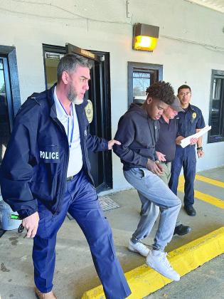 Mamou Assistant Chief of Police Caleb Semien (left) and Officer Steven Ardoin (right) escort Dorian Thomas (center) out of the police station. Also pictured is Mamou Chief of Police Pat Hall. (Photo submitted)