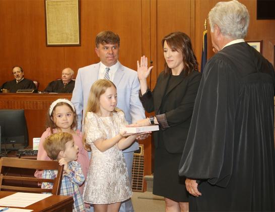 Laura Rougeau Garcille recites her oath of office delivered by State Supreme Court Judge James Genovese on Wednesday in the St. Landry Parish Courthouse. With her is her husband, Brett, and children, Emmy, 9, holding a Bible, Riley 7 and John Roth, 4. Seated in the background are District Judges Gregory Doucet and James Dotherty. (LSN photo by Harlan Kirgan)