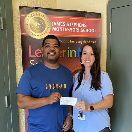 Chris Serie (left) presents a $500 donation to James Stephens Montessori Principal Melanie Bordelon for the school’s athletics program. (Photo courtesy of Melanie Bordelon)
