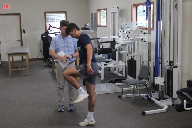 Clay Landreneau (left), a physical therapist at Healthworks Rehab, performs a physical examination on Sacred Heart’s Boyce Schexnider (right). (Gazette photo by Rhett Manuel)