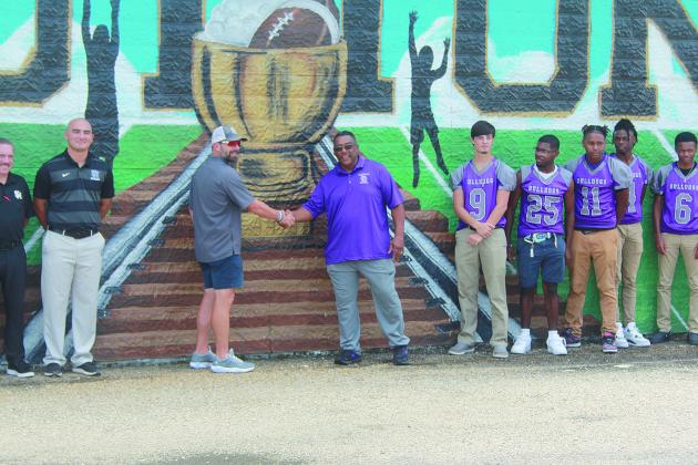 Sacred Heart head coach Josh Harper (left) and Ville Platte High head coach Roy Serie (right) exchange a hand shake in front of the Tee Cotton Bowl mural. (Gazette photo by Tony Marks)