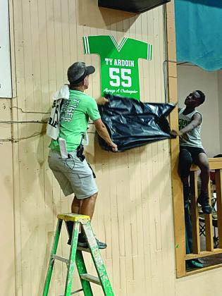 Chataignier Elementary basketball coach Duncan Johnston (left) and Zion Thomas (right) unveil Ty Ardoin’s retired number 55 jersey. (Gazette photo by Rhett Manuel)
