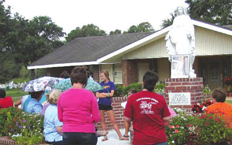 Praying the Rosary (2012) around the Virgin Mary statue after it was moved to the front lawn of the rectory. Several Redlich family members were in attendance including Lyle and Lowell, twin sons of Oris Redlich, visible at far left. (from the files of The Basile Weekly)