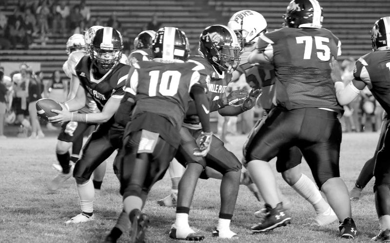 Bulldog quarterback Bastian Veillon (7) hands the ball off to a teammate last week against Port Barre. (Photo courtesy of Susan Angelle Photography)