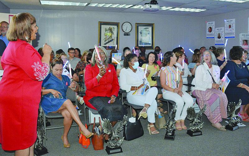 Teacher of the Year Coordinator Grace Sibley (left) leads a chorus of “This Little Light of Mine” during the Evangeline Parish School Board Meeting held Wednesday, June 22. Recognized during the meeting were the current and former teachers or principals of the year who made it to the state level. Seated from left on the front row are Emee Aswell, Lisa Celestine, Kayla Joseph Jones, Heather Demourelle, Christine Bacon, Liz Chatelain, and Cherie Fontenot.