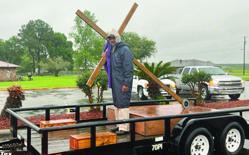Reverend Matthew Alfred Jr., moderator of the Eastern Seventh District Association, carries the cross as the motorcade departs from Mt. Pilgrim Baptist Church, on Pine Point Road. The event, on Good Friday, culminated with meditations on the Last Seven Sayings. (Gazette photo by Tony Marks)