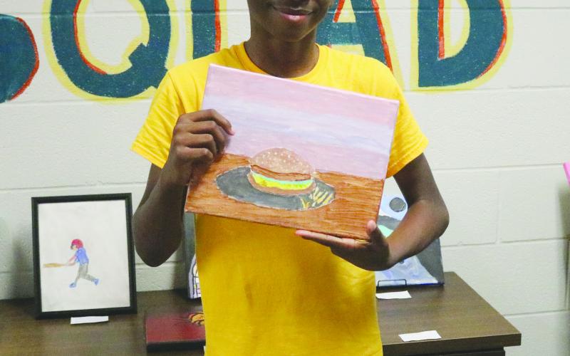 Derrion Denton, a seventh grade student of Evangeline Reimagine Academy, shows off one of his pieces of art which was on display on Wednesday, May 22. (Gazette photo by Tony Marks)
