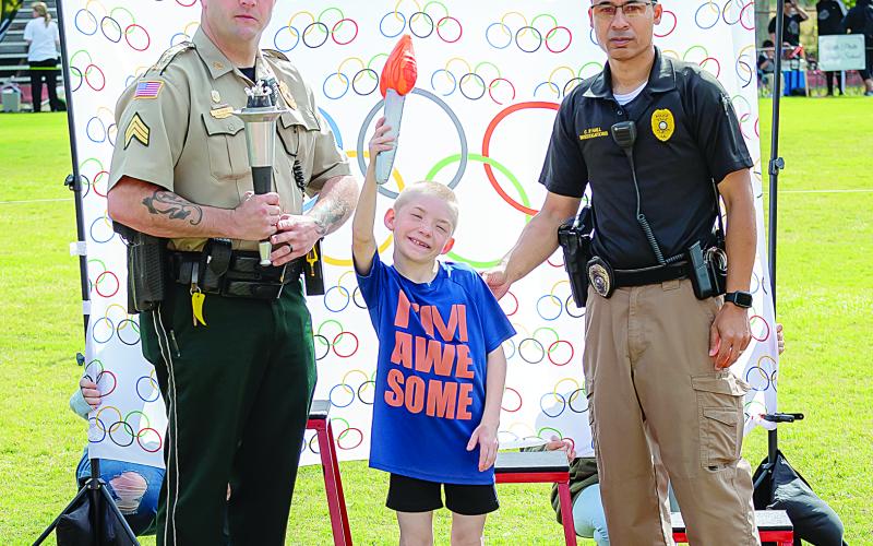 James Stephens Montessori student James LeBlanc (center) hoists the Special Olympic flame at the event held Tuesday, March 29, in Basile. Also pictured are Basile police officer Daniel Crum (left) and Ville Platte police officer Pat Hall. (Photo courtesy of Tim Comeaux)