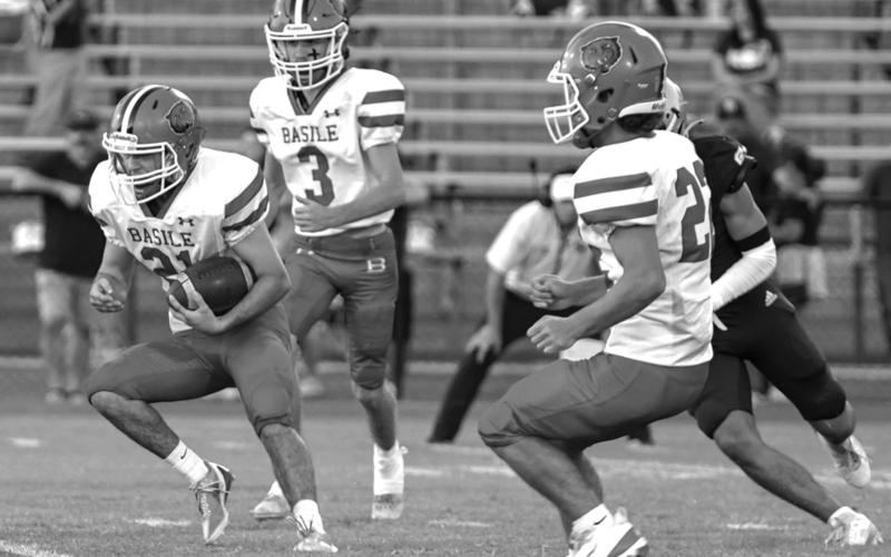 Basile High’s Kye Smith (21) puts the ball into play against Sacred Heart with teammates Sayg Smith (3) and Logan Bergeron (22) by his side. (Photo by Tonya Ortego)