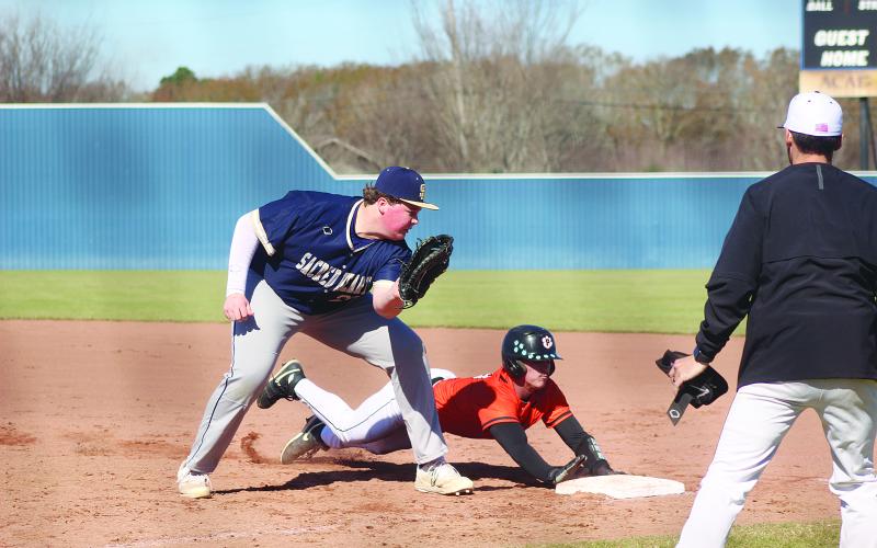 Weston Byrd (10) slides underneath the tag from Sacred Heart first baseman Liam Vidrine (28) as the Pine Prairie Panthers took on the Trojans in the Perry Pitre Baseball Jamboree. (Gazette photo by Tony Marks)