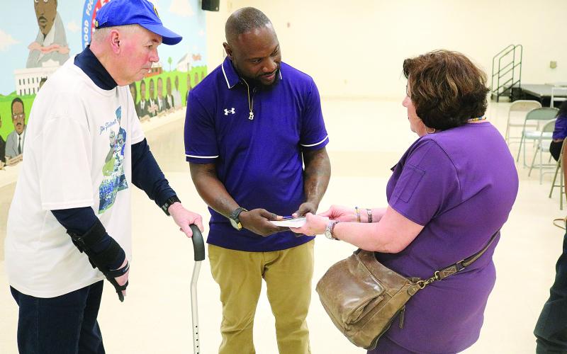 Suzy Fontenot (right) presents new Ville Platte High School head football coach Chris Bland (center) with a copy of Sharpened Iron: The Tee Cotton Bowl Story. Pictured on the left is Tee Cotton Bowl co-founder Tim Fontenot. (Gazette photo by Tony Marks)