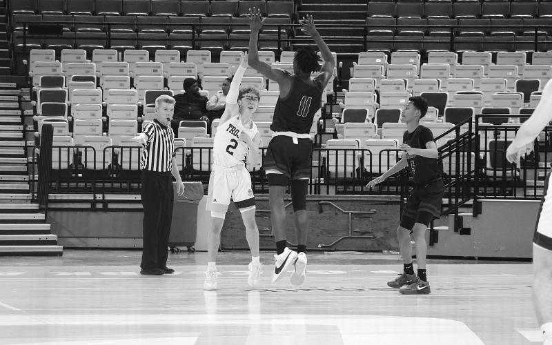 Hayden Deshotel (2) passes the basketball while being defended by Geo Next Generation’s Alonzo Knighten in a Trojan 63-46 win on Saturday.