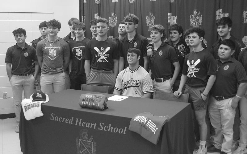 While flanked by members of the Sacred Heart baseball team, Briggs Ardoin (seated) is pictured after signing to continue his playing career at Baton Rouge Community College. Among those also pictured are Ellis Fusilier, Parker Feucht, Hayden Droddy, Sam Veillon, Nick Fontenot, Everett Johnson, John Michael Duplechin, Jackson Bruney, Boyce Schexnider, Brad Fusilier, Wade Pitre, and Sam Richardson.