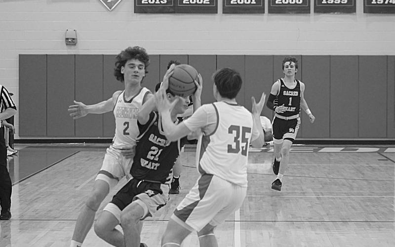 William Jorden (21) looks to get rid of the basketball while being defended by two Central Private players in Sacred Heart’s 57-43 loss in the first round of the Division IV Select playoffs. (Gazette photo by Tony Marks)
