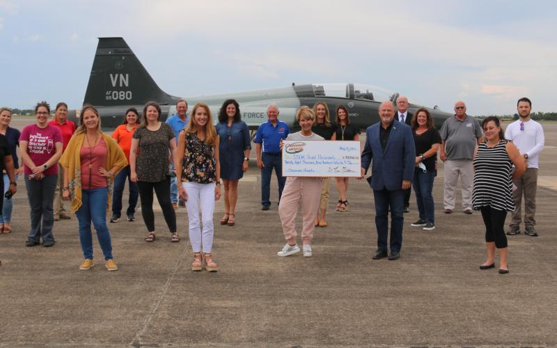 Retired Col. Kevin Melton and 2021 Airshow director Mary Jo Bayles, seen here holding an oversized check, are surrounded by the grant recipients, who include Christina Lejeune, Basile High. Airshow board members, seen in the back row, joined in for the presentation. (Photo submitted)