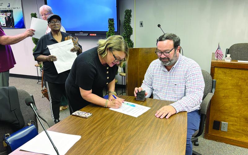 Cheri Fontenot (center) is pictured as she signs her contract to officially become the new school superintendent. Seated is Assistant District Attorney Jacob Fusilier, who notarized the contract. Also pictured on the left is Evangeline Parish School Board Vice President Sheila Joseph. (Gazette photo by Tony Marks)