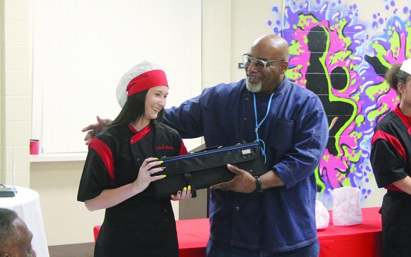 Chef Terryl Jackson (right) presents a knife set to Chef Mattie Buller (left) as she graduates from the Flat Town Culinary Academy on Thursday, July 21. Buller was part of the second group of Ville Platte Girls-Boys Place members to participate in the academy. (Gazette photo by Tony Marks)