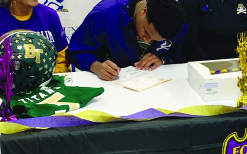 While flanked by family members, Ville Platte native Kieran Davis (center), signs his national letter of intent to play college football at East Carolina University. (Gazette photo by Rhett Manuel)