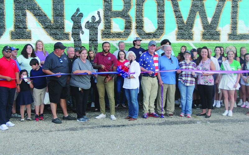 Among those pictured at the Tee Cotton Bowl mural dedication ceremony are (from left) Chris and Connie Lamke, Thaddaeus Arvie, Dr. Gwen Fontenot, Tim Fontenot, Ronnie and Joan Landreneau, Renee Brown, and Queen Cotton Shelbi Rials. (Gazette photo by Tony Marks)