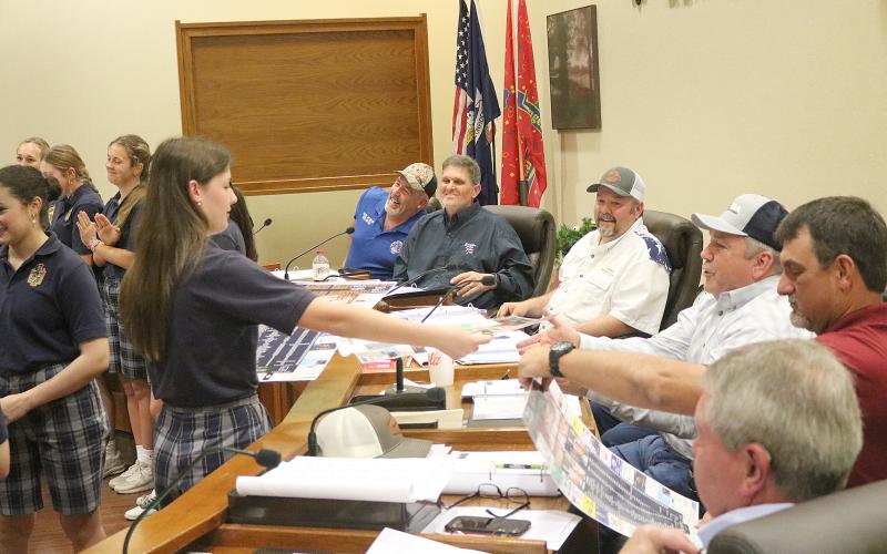 Kali Shiver (left) hands Evangeline Parish Police Juror Tim Causey (right) a basketball schedule poster that was signed by the members of the Sacred Heart girls’ team that advanced to the state basketball tournament for the first time in school history. All police jurors received a similar poster. Also pictured (from top on the right) are jurors Keith Saucier; Kevin Veillon, vice president; Bryan Vidrine, president; Ryan Ardoin; and Brent Guillory. (Gazette photo by Tony Marks)