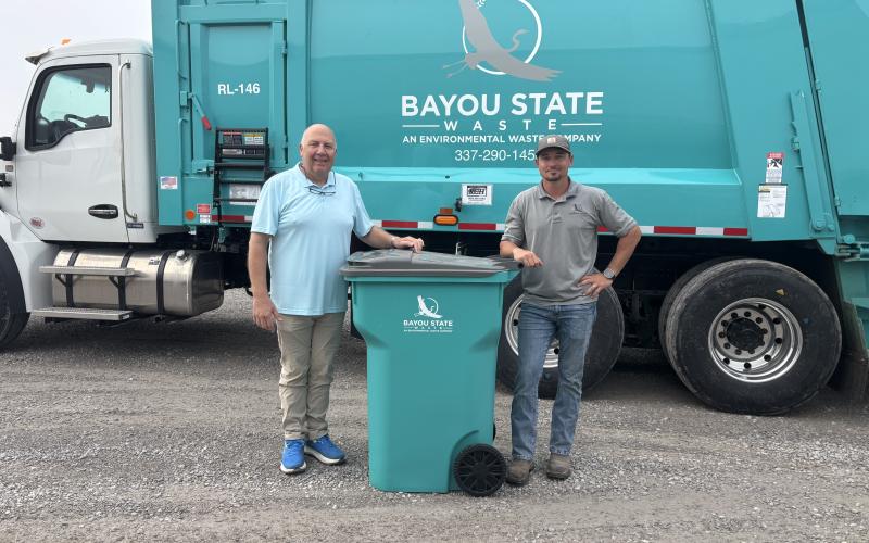 NEW TRASH SERVICE COMING TO EVANGELINE PARISH - Bayou State Waste will begin taking over garbage collection for Evangeline Parish starting June 30. Evangeline Parish Solid Waste Director Pat Derouselle (left) and Bayou State owner Jake Lavergne (right) are shown with one of the cans that each household in the parish will receive as part of the new contract with the company. (Gazette photo by Heather Bogard)
