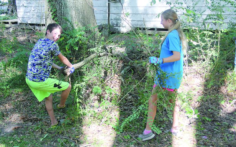 AJ (left) and Abby Rose (right) are pictured as they gather branches inside the Ville Platte Native Plant Heritage Garden.