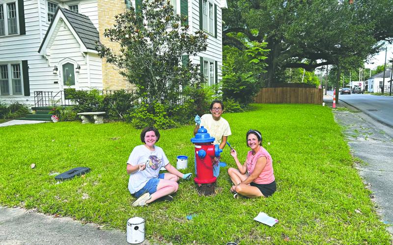 HYDRANTS GET A PATRIOTIC FACELIFT - From left, Kate LaCaze, Sarahi Sawtelle and Nina David are shown as they paint one of six fire hydrants along Magnolia Street. (Photo courtesy of Nina David)