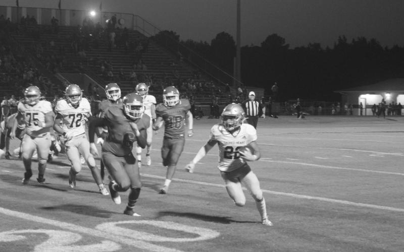 Trojan speedster Ike Perry (22) tries to elude a would-be tackler in Sacred Heart’s 13-0 loss to Caldwell Parish Thursday night. The Trojans now host Catholic-P.C. in a district contest. (Gazette photo by Tony Marks)