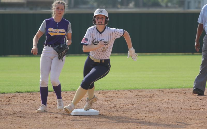 Catherine Larson (12) sets her eyes on Sacred Heart head softball coach Todd Ardoin, who coaches third base, as she rounds the second base bag in a 15-0 win over Westgate. (Gazette photo by Tony Marks)
