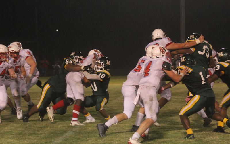 The stingy Mamou defense, led by Jaclarion Fontenot (58) and Christian Broussard (10), picks up a stop against Port Barre as the Green Demons earn a 43-12 victory. (Gazette photo by Tony Marks)