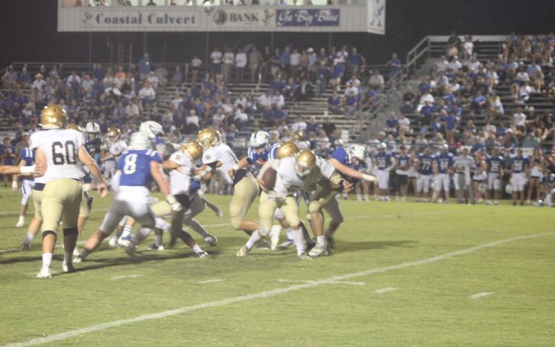 Sacred Heart’s signal caller Ethan Karonika (5) tries to stay on his feet as he is met by the St. Ed’s defense last week in Eunice. Karonika and the rest of the Trojans are hosting Opelousas Catholic on homecoming night tomorrow for the district title. (Gazette photo by Rhett Manuel)
