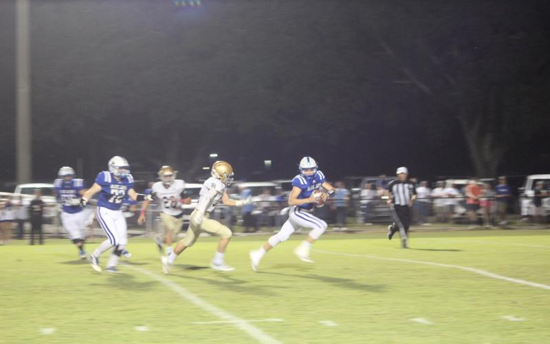 Ellis Shipp (14) tries to keep pace with St. Ed’s quarterback Luke Vidrine in the Trojans’ meeting with the Blue Jays in the regular season. That game was a 40-7 win for the visiting Trojans, and the two squads meet again in the playoff opener tomorrow night at Soileau-Landry Field. (Photo by Gazette photo by Rhett Manuel)