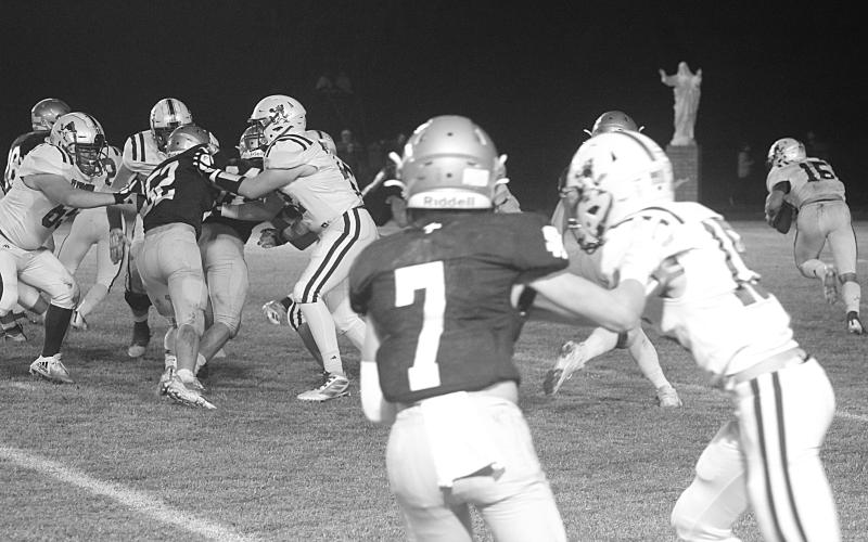 The Sacred Heart defense led by Hayden Droddy (7) and Beau St. Romain (52) combines for a stop deep inside Blue Jay territory in the Trojans’ playoff win against St. Ed’s last week. (Gazette photo by Rhett Manuel)