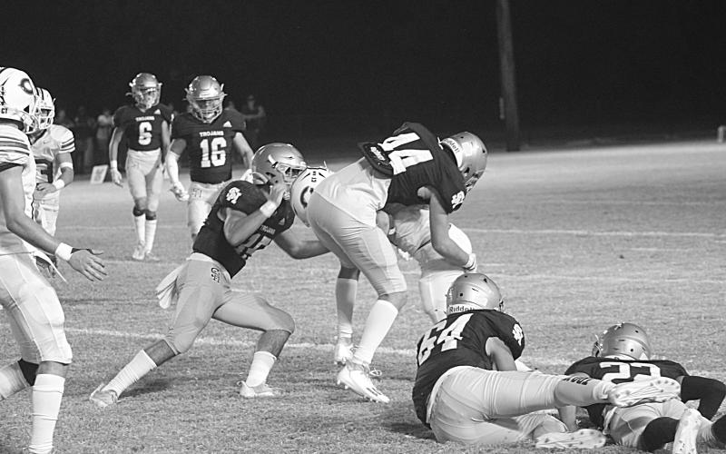 Defenders of Troy, led by Wade Pitre (15), combine for a stop against the Hornets of Catholic-Pointe Coupee in the teams’ district opener Thursday night. (Gazette photo by Rhett Manuel)