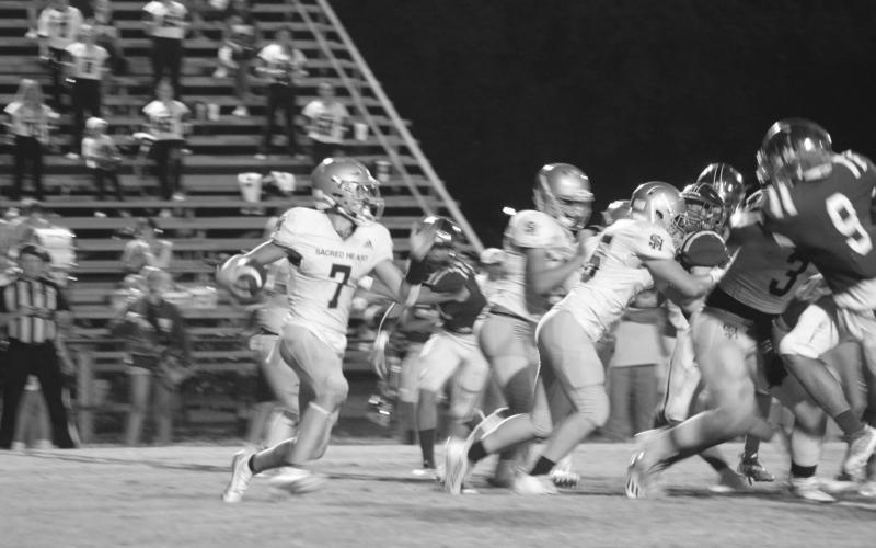 Trojan quarterback Hayden Droddy (7) finds running room against St. Edmund. (Gazette photo by Rhett Manuel)