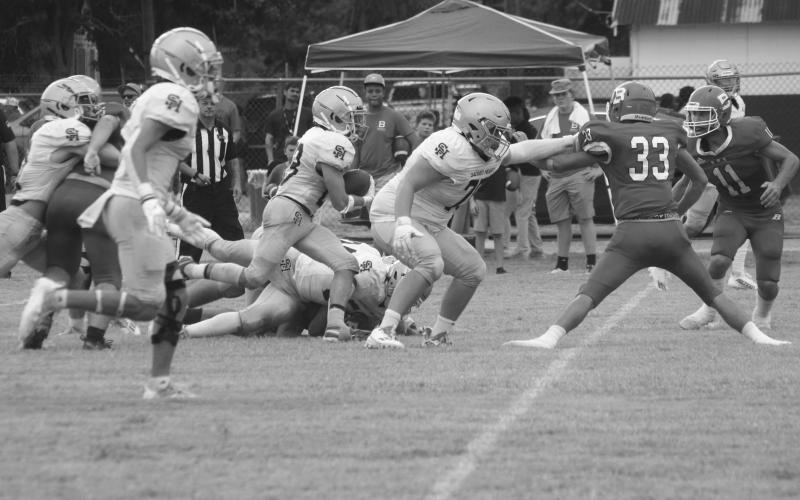 Jude Hebert (23) gets a block from a Trojan teammate and finds a running lane in Sacred Heart’s win against Basile in the opening contest of the jamboree. (Gazette photo by Rhett Manuel)
