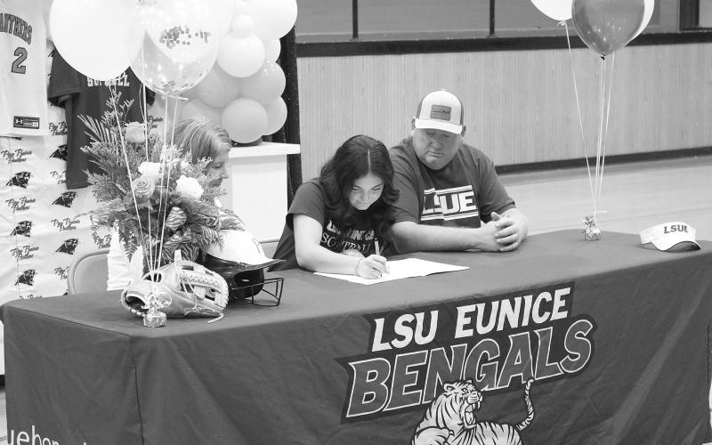 Ava Kordish (center) signs the paperwork to officially join the LSUE softball team during a ceremony held inside the Pine Prairie gym on Tuesday, November 14. Also pictured are her mother, Shelly Kordish; and her father, Skylar Kordish. (Gazette photo by Tony Marks)