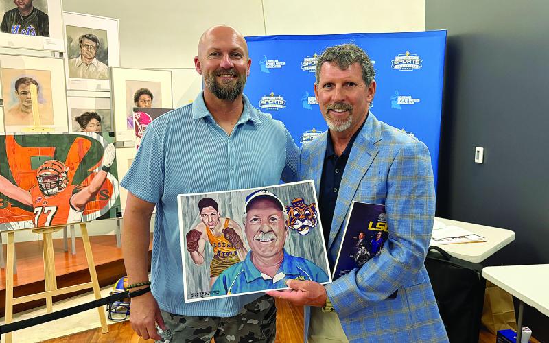 Artist Christopher Brown (left) presents artwork to Robert Soileau (right). The artwork commemorates Robert’s father George “Bobby” Soileau’s induction into the Louisiana Sports Hall of Fame.