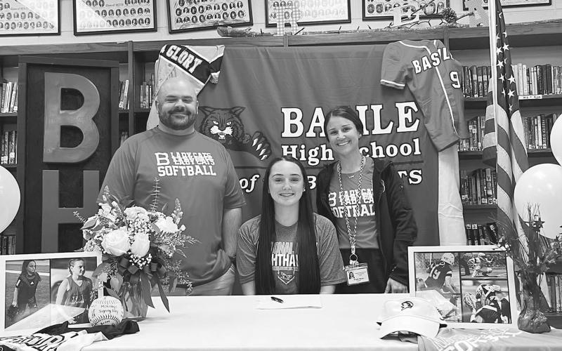 McKinley Guillory (seated) is flanked by Bearcat softball coaches Collins Barnes and Kristen Bacon during the recent letter of intent signing for the Basile High School softball senior.