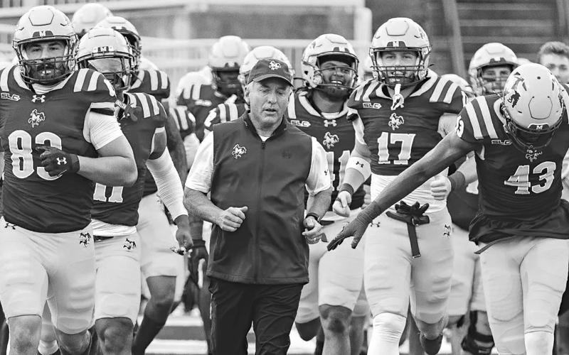 McNeese football coach Matt Viator runs onto the field with his team before a game last season. (Photo courtesy of McNeese Athletics)