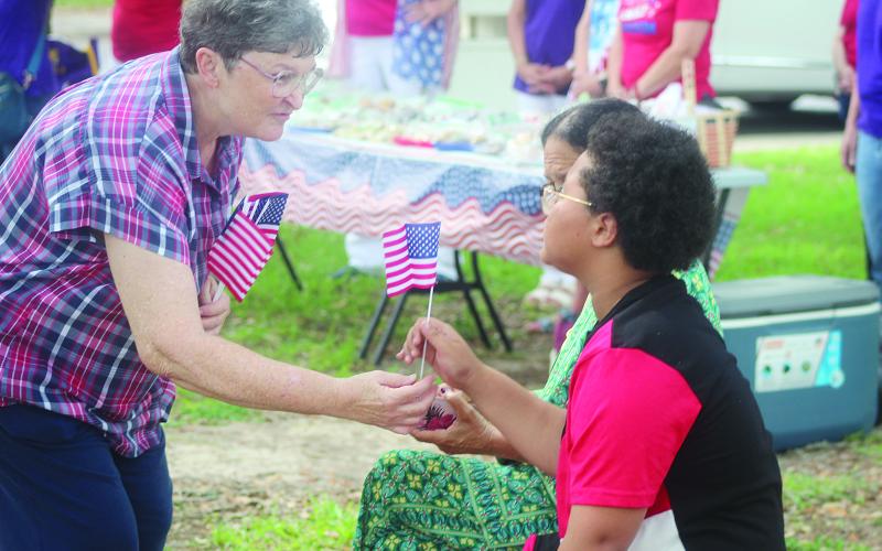 This photo of Debbie Fontenot (left) handing out American Flags during the Memorial Day observance at the Evangeline Parish Courthouse won 3rd place in Best News Photo. (Gazette photos by Tony Marks)