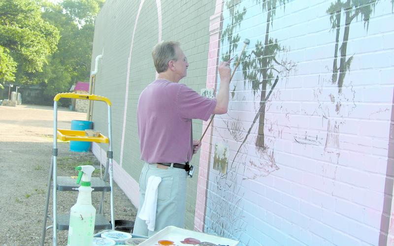 Local artist Waven Boone is shown filling in the sketched panels of his mural “The Spirit of Ville Platte.” (Gazette file photo by Heather Bogard)