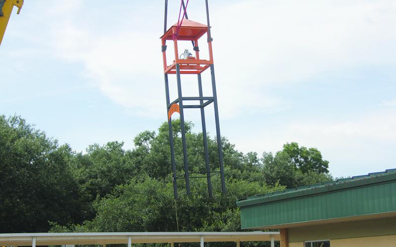 The new bell tower is pictured as Louisiana Crane hoists it over the covered walkway and places it in position at Pine Prairie High School on Tuesday, July 26. (Gazette photo by Tony Marks)