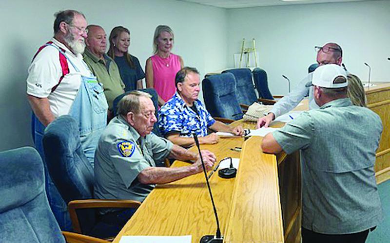 After the Pine Prairie Council meeting on Thursday, August 10, a donation of property was signed. Pictured standing on the left (from right) are Councilwoman Tammy Buxton, Kristy Ardoin, and Councilmen Kevin Rodriguez and Gilbert Bordelon; seated on the left (from right) are Mayor Quint West and Chief of Police LC Deshotel; standing on the right are Village Attorney Greg Vidrine and Lelia and Derrick Thrasher. (Gazette photo by Tony Marks)