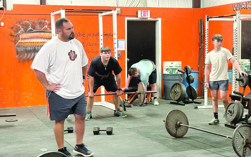 Pine Prairie head football coach Lance Myers (left) watches as members of the team lift weights during summer workouts. (Gazette photo by Tony Marks)