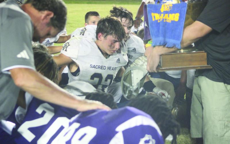 Sacred Heart’s Isaac “Ike” Perry (23) takes a knee during the prayer following Tee Cotton Bowl XVIII earlier this season. (Gazette photo by Rhett Manuel)