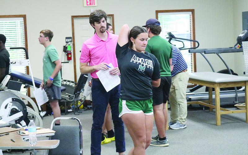 Physical therapist Austin Dufrene (left) observes Mamou’s Madison Savoy (right) as she goes through a musculoskeletal screening. (Gazette photos by Tony Marks)